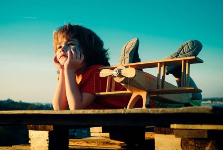 Photo for Dreams of flight. Child 6 year old playing with toy plane against the sky. Dreams of travels. Little dreaming child with a toy airplane plays outdoors - Royalty Free Image