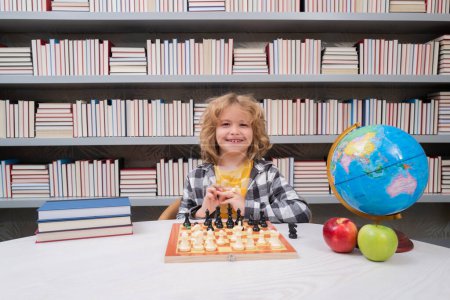 Foto de Juega al ajedrez. Un niño listo pensando en ajedrez. Retrato de un chico listo con tablero de ajedrez. Chico jugar ajedrez - Imagen libre de derechos