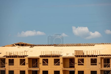 Téléchargez les photos : Cadrage et toiture. Cadre en bois d'une maison contre un ciel bleu. Le cadre du chalet. Le début de la construction de la maison. Site de construction. Maison Cadre en bois - en image libre de droit