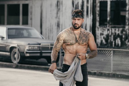 Photo for Tattooed gangster on crime street. Crime Hispanic gang members. Gangsta Crimes style. Hispanic burglar. Ethnic angry Crime man. Crime Man with tattoo on strong body outdoor. Street style - Royalty Free Image