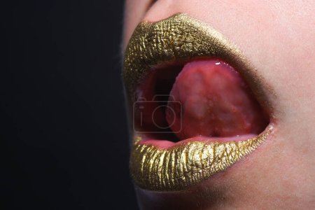 Foto de Lamiendo labios sexy lengua. Boca de mujer sensual. Sexy chica labios dorados, boca de oro. Piel dorada brillante y labios dorados. Brillo metálico brillo labial dorado - Imagen libre de derechos