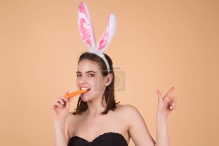 Téléchargez les photos : Easter girl. Young woman wearing Easter bunny ears holding decorative colored eggs on studio background with copy space - en image libre de droit
