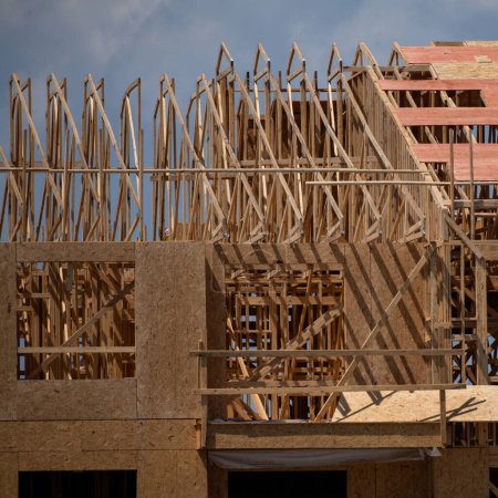 Photo for Wooden roof building. Standard timber framed building with roof trusses. Roof Frame house. The frame of the new build home. Construction site. Roof trusses constructed with construction beams timber - Royalty Free Image