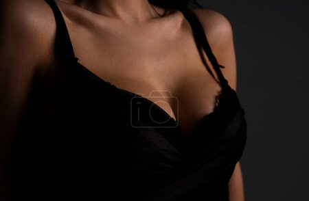 Foto de Lingerie concept. Sexy breas, boobs in bra, sensual tits. Beauty slim female body. Closeup of sexy girl boob in black bra - Imagen libre de derechos
