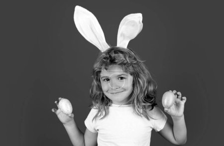 Photo for Portrait of kids boy in bunny ears hunting easter eggs outdoor. Child having easter isolated on blue background - Royalty Free Image