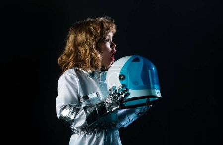 Téléchargez les photos : Garçon excité jouant pour être un astronaute avec casque spatial et combinaison en métal - en image libre de droit