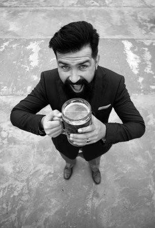 Foto de Hombre divertido en traje clásico sosteniendo vaso con cerveza en la mano. Hombre sonriente con cerveza. Camarero, cervecero feliz. Longitud completa, gran ángulo. Emociones de expresión - Imagen libre de derechos