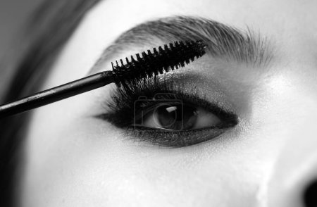 Photo for Closeup of eye makeup. Applying maskara on lushes Young woman getting make up with brush. Eyes visage woman - Royalty Free Image