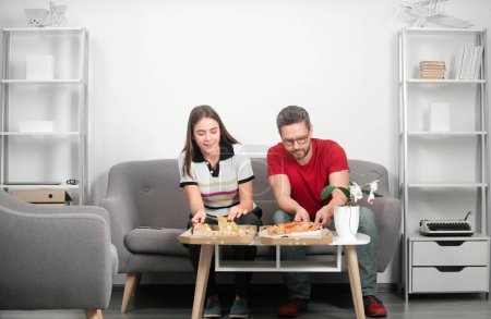 Téléchargez les photos : Homme d'affaires et femme d'affaires faisant une pause déjeuner au bureau, mangeant une tranche de pizza - en image libre de droit