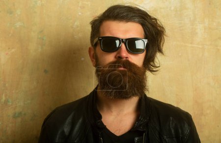 Téléchargez les photos : Un hipster barbu. Visage d'un homme avec des lunettes noires. Macho a l'air confiant. Hipster barbu - en image libre de droit