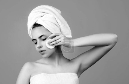 Foto de Mujer de belleza tocando mejilla con esponja, piel natural sana. Retrato de una joven atractiva con una toalla de baño en la cabeza. Hermoso retrato de cara mujer - Imagen libre de derechos
