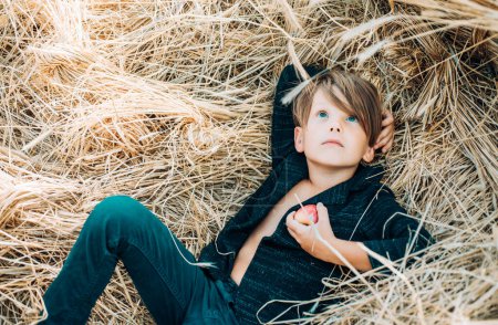 Photo for Kid boy holding gold leaf and lies on the hay. Sale for entire autumn collection, incredible discounts and wonderful choice. Back to school. Bye summer - hi autumn - Royalty Free Image