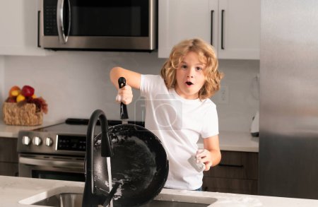 Foto de Retrato de un niño de 7-8 años lavando los platos en casa. Niño lavando los platos en el fregadero de la cocina - Imagen libre de derechos