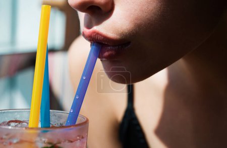 Téléchargez les photos : Gros plan des lèvres des femmes buvant avec de la paille rose. Un cocktail pour femme. Gros plan mouillé lèvres sexy - en image libre de droit