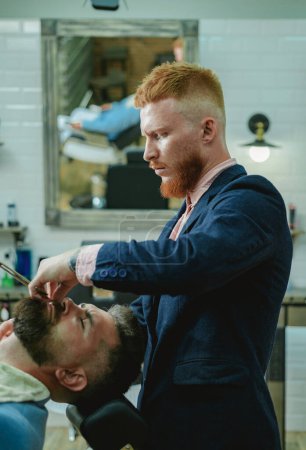 Hair salon and barber vintage. Brutal guy in modern Barber Shop. Trims. Great time at barbershop. Barber making haircut of attractive bearded man in barbershop