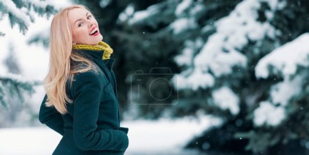 Téléchargez les photos : Joyeux sourire femme d'hiver en hiver fond neigeux en plein air. Portrait de jeune belle femme vêtue d'un manteau. Modèle marche dans la rue d'hiver - en image libre de droit