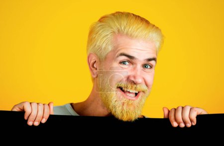 Foto de Hombre sonriente sosteniendo una hoja de papel en blanco, aislado sobre fondo amarillo - Imagen libre de derechos