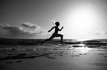 Photo for Woman running on beach. Beautiful young girl in sportswear running on sea - Royalty Free Image