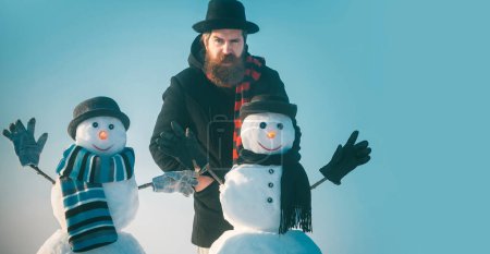 Téléchargez les photos : Hiver bonhomme de neige en chapeau jouer avec bonhomme de neige en plein air. Homme avec bonhomme de neige sur fond d'hiver extérieur. Bonhomme de neige pour bannière d'hiver - en image libre de droit
