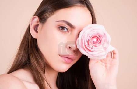 Foto de Retrato de estudio de una joven hermosa mujer con rosas. Retrato de cerca de una hermosa joven con una rosa rosa cerca de la cara - Imagen libre de derechos