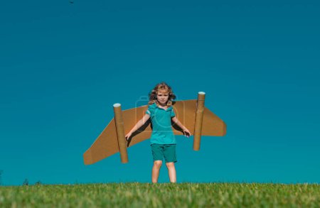 Photo for Kid imagination, child pilot with paper wings having fun at outdoor. Summer vacation and travel concept - Royalty Free Image