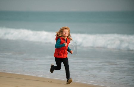 Téléchargez les photos : Des enfants qui jouent sur la plage. Les enfants jouent en mer pendant les vacances d'été en famille. Enfant coureur joggeur courir dans la nature. Mode de vie sain et actif des enfants - en image libre de droit