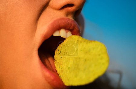 Photo for Pleasure eating potato chips. Close up female mouth eat potato chips. Chips with teeth. Tasty delicious fast food. Eating crisps. Fast food - Royalty Free Image