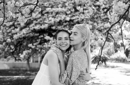 Foto de Chicas de primavera en flores. Retrato al aire libre de joven hermosa feliz sonriente pareja femenina posando cerca del árbol floreciente - Imagen libre de derechos