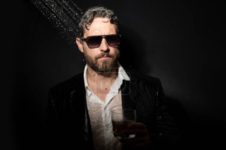 Photo for Night lifestyle. Disheveled man in suit in bathroom after night party. Man drinking a whiskey after party in night club. Alcohol and drugs concept. Stressed business man under shower in bath at night - Royalty Free Image