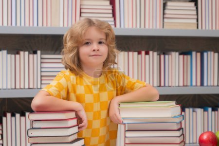 Téléchargez les photos : Child reading book in a book store or school library - en image libre de droit
