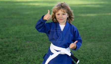 Photo for Kid boy exercising karate kataoutdoor. Sport karate kids. Little boy wearing kimono doing karate in park. Sport child with boxing gloves training box. Little fighter. Martial arts for kids. Kids sport - Royalty Free Image