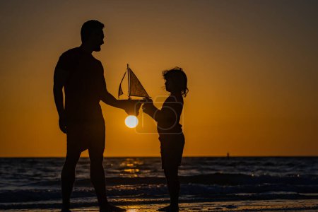 Photo for Father and son dream on travel. Father and son enjoying sunset play toys sailing boat. Summer travel, family holidays. Journey trip lifestyle marine concept. Parenting, fatherhood and fathers day - Royalty Free Image