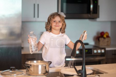 Téléchargez les photos : Drôles jumeaux garçons aider dans la cuisine avec laver la vaisselle. Les enfants s'amusent avec les travaux ménagers. Enfant garçon lave la vaisselle à l'intérieur de la cuisine. Enfant aidant ses parents avec les travaux ménagers - en image libre de droit