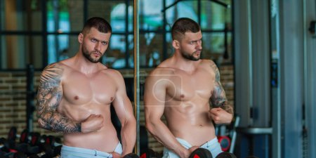 Foto de Sportsman muscular man workout in gym. Athletic man exercising with dumbbell. Fitness, sports concept, sport club, fitness center. Workout in gym. Sexy guy bodybuilder with perfect muscles body - Imagen libre de derechos