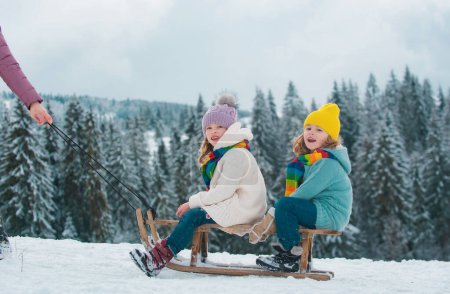 Photo for Funny boy and girl having fun with a sleigh in winter. Cute children playing in a snow. Winter activities for kids. Family christmas holiday outdoor - Royalty Free Image