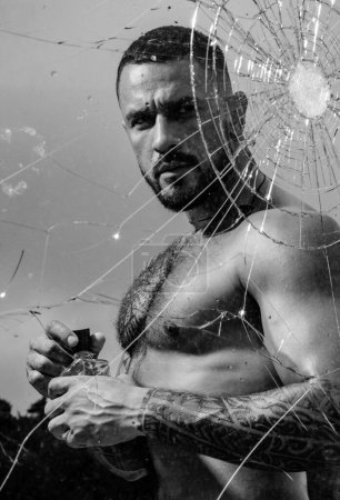 Photo for Mental problem. bullet hole in glass. broken glass because of hit. sexy hispanic man broken mirror. anger. destruction. macho man behind crushed glass. crush test. theft. emotional discharge. - Royalty Free Image