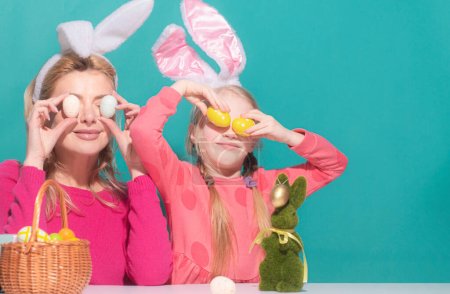 Foto de Familia feliz preparándose para la Pascua. Madre e hija pintando huevos. Linda niña pequeña con orejas de conejito - Imagen libre de derechos