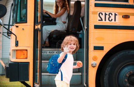 Foto de Niño de la escuela en la parte delantera del autobús escolar con manzana y bolsa - Imagen libre de derechos