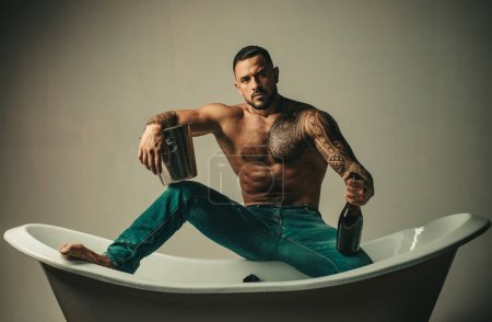 Photo for Muscular man sit on bathtub in bathroom, men holiday with champagne. Celebrating christmas or birthday. Private sex party - Royalty Free Image