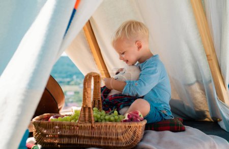 Téléchargez les photos : Des enfants campent. Joyeux enfant en tente. Un garçon jouant dans une tente. On s'amuse dehors. Camping - en image libre de droit
