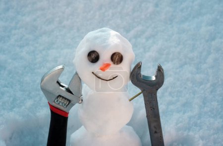 Téléchargez les photos : Petit bonhomme de neige avec des outils de réparation constructeur. Joyeuses vacances et célébration - en image libre de droit