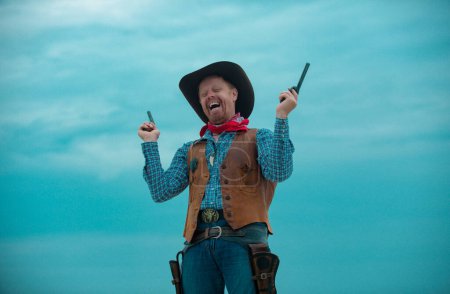 Téléchargez les photos : Voulait western. Joyeux cow-boy drôle avec une arme. Bandit américain, homme occidental avec chapeau. Ouest et armes - en image libre de droit