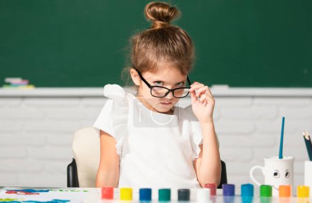 Photo for Child girl drawing with coloring pens paintind. Portrait of adorable little girl smiling happily while enjoying art and craft lesson in school. Funny school girl face with glasses - Royalty Free Image