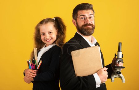 Photo for Teacher with happy pupil school girl. Portrait of funny school girl and tutor with school supplies. Happy teacher and student girl on yellow. Back to school, student girl in uniform - Royalty Free Image