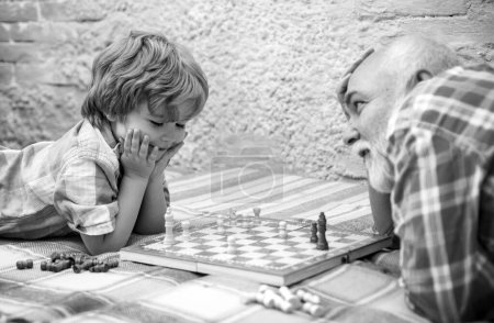 Foto de Pieza de ajedrez. Concepto de abuelo y nieto. El apuesto abuelo y nieto están jugando ajedrez mientras pasan tiempo juntos en casa. - Imagen libre de derechos