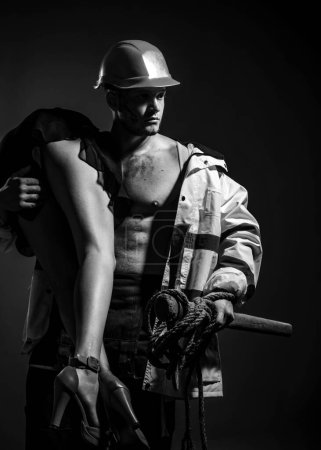 Photo for Dominating in the foreplay sexual role play. Firefighters sexy body muscle man holding saved sexy woman. Risky occupations concept. Firefighter - Hot and sexy - Royalty Free Image
