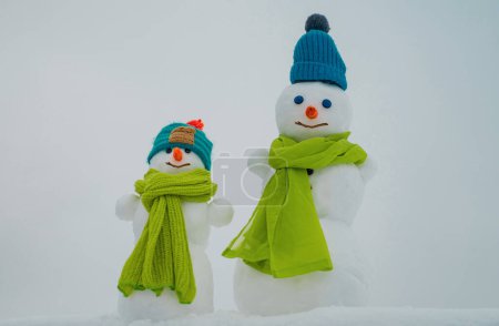 Téléchargez les photos : Bonhomme de neige. Deux bonhomme de neige sur fond de neige. Bonhomme de neige drôle sur une prairie enneigée sur un fond de neige - en image libre de droit