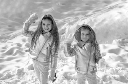 Foto de Feliz invierno. Dos niñitas jugando con nieve en el parque. Retrato de dos niñas jugando con nieve en invierno. Linda hermanas jugando en una nieve - Imagen libre de derechos