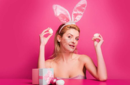 Téléchargez les photos : Femme avec des oreilles de lapin tenir oeuf de Pâques sur fond rose - en image libre de droit