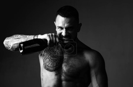 Photo for Brutal handsome latinos with tattooed body opens his teeth champagne. Champagne or wine bottle. Wine celebration concept - Royalty Free Image